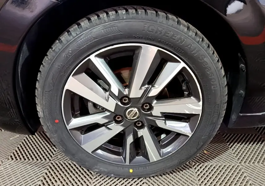 Gros plan sur la roue avant droite d'une Nissan Micra noire, mettant en valeur la jante alliage au design moderne.