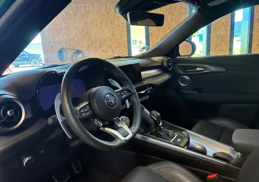 Vue intérieure côté conducteur de l'Alfa Romeo Tonale 1.5 MHEV 2022 avec tableau de bord noir et volant cuir.