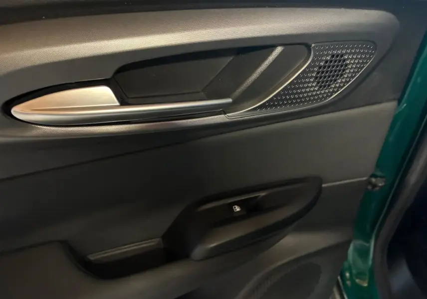 Gros plan sur la poignée intérieure côté gauche de la porte avant d’une Alfa Romeo Tonale vert foncé, avec bouton de verrouillage.