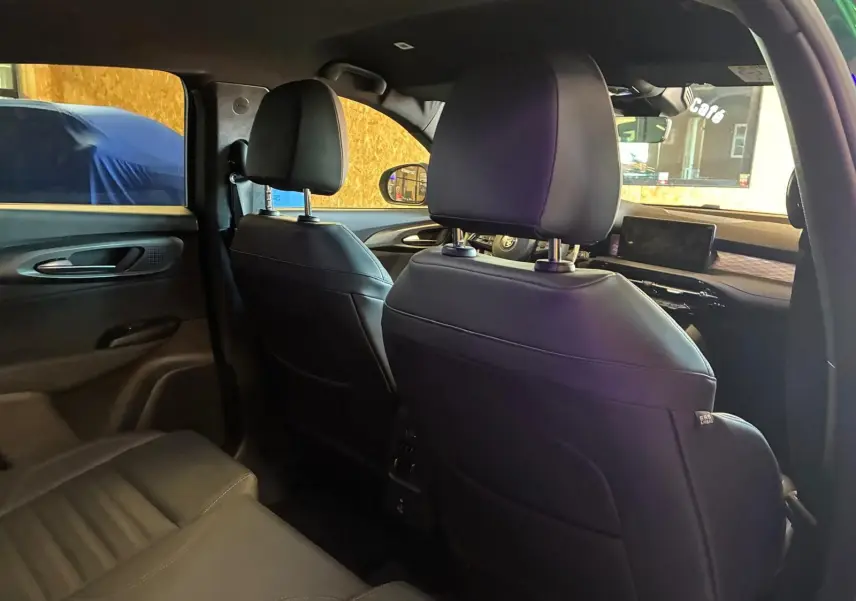 Vue intérieure arrière de l'Alfa Romeo Tonale 2022, sièges en cuir noir et tableau de bord visible côté droit.