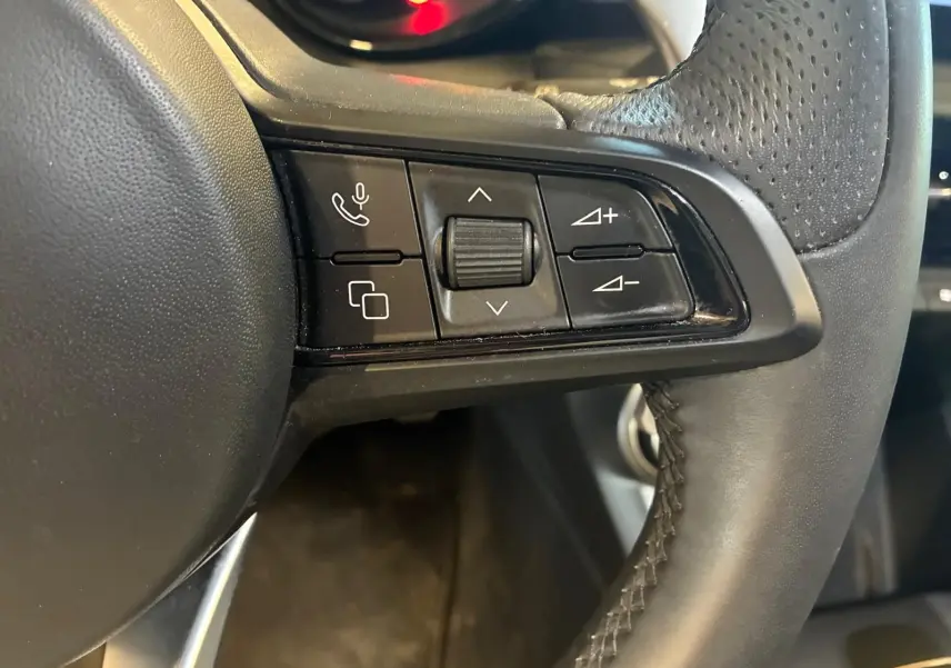 Gros plan sur les commandes gauche du volant en cuir noir perforé de l'Alfa Romeo Tonale 2022.