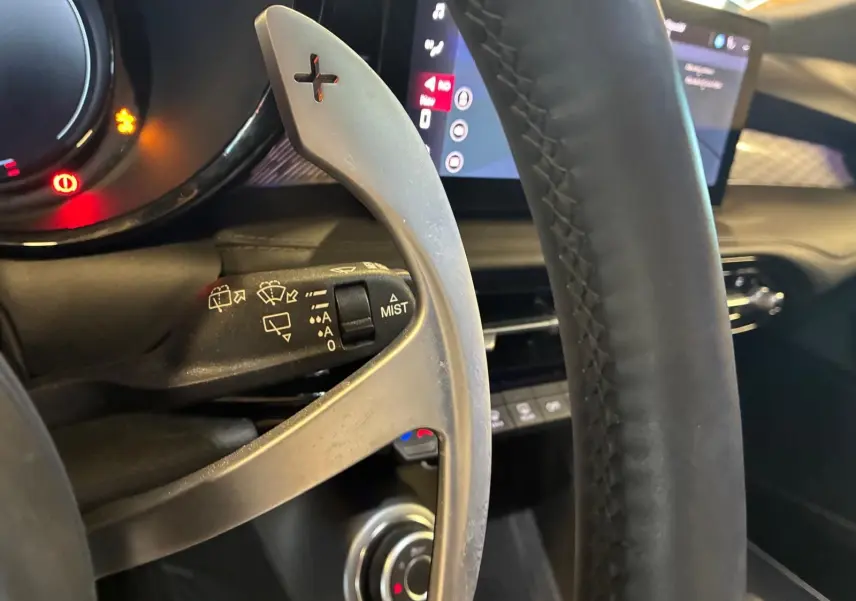 Gros plan sur la palette de changement de vitesses à droite du volant en cuir noir de l'Alfa Romeo Tonale vert foncé.