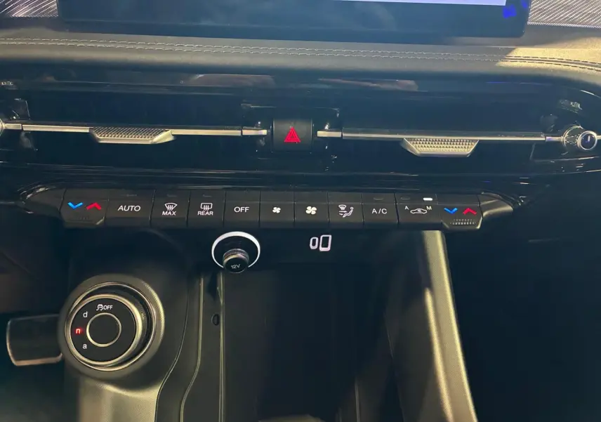 Vue rapprochée de la console centrale de l'Alfa Romeo Tonale 2022, avec commandes climatisation et bouton de sélection de mode de conduite.
