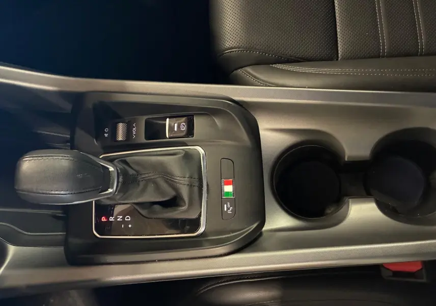 Gros plan sur la console centrale noire de l'Alfa Romeo Tonale avec levier de vitesse automatique et drapeau italien.
