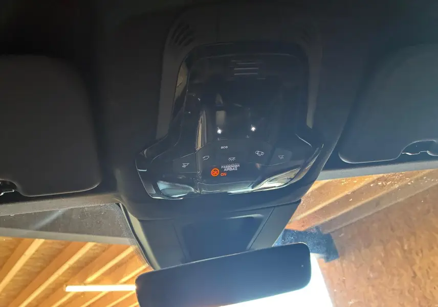 Vue intérieure en plongée du plafonnier et du rétroviseur d'un Alfa Romeo Tonale vert foncé, avec indicateur airbag passager allumé.