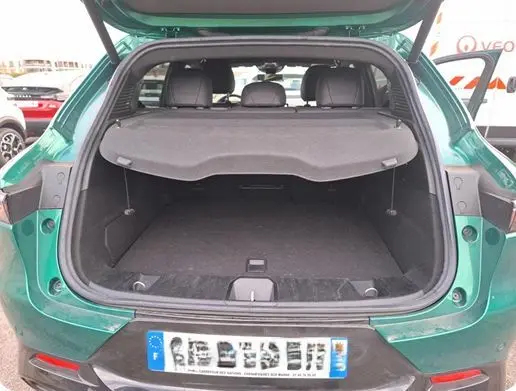 Vue 3/4 arrière droite d'une Alfa Romeo Tonale vert foncé avec jantes distinctives à cinq cercles, stationnée en intérieur.