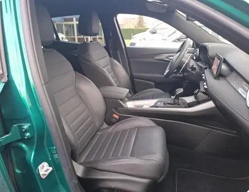 Vue de profil côté gauche d'un Alfa Romeo Tonale vert foncé avec jantes distinctives en intérieur bois.