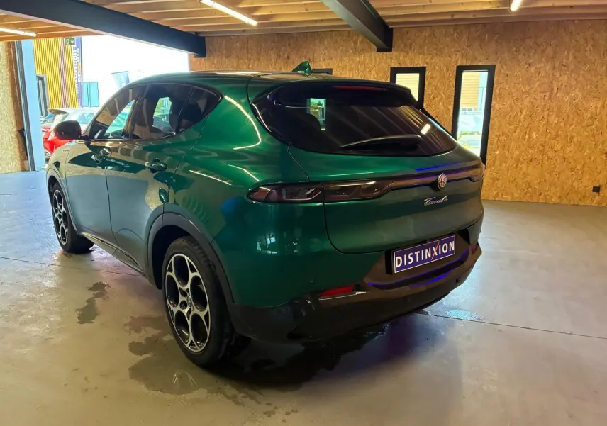 Vue 3/4 arrière droite de l'Alfa Romeo Tonale vert foncé, avec feux arrière fins et jantes distinctives en cercle.