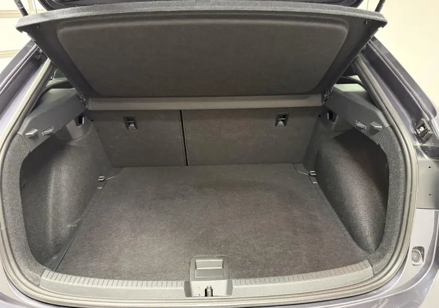 Coffre ouvert vu de face d'un Volkswagen Taigo gris cendre, montrant un espace de chargement propre et spacieux.