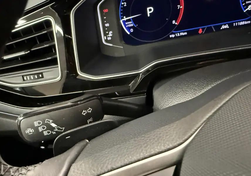 Gros plan sur le combiné d'instruments digital et la commande de clignotants du Volkswagen Taigo gris cendre, intérieur noir.