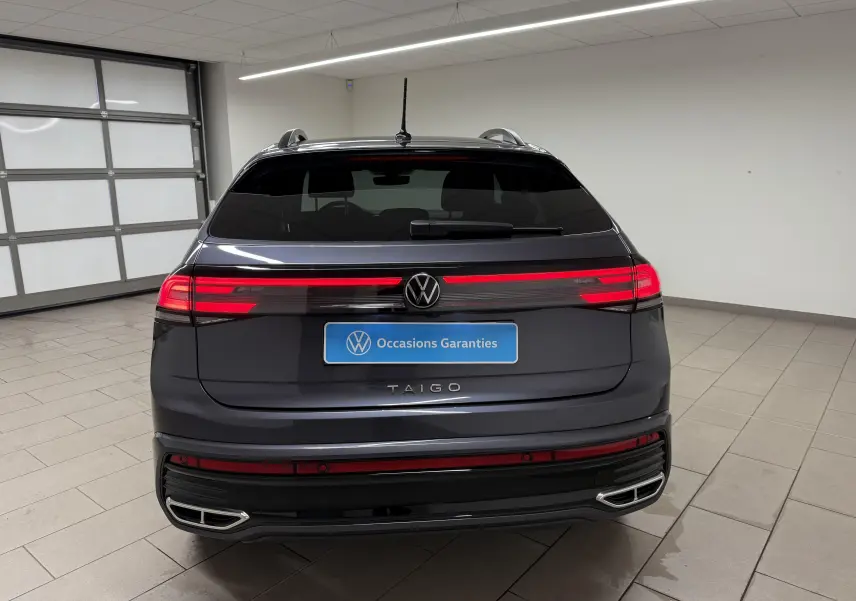 Vue arrière du Volkswagen Taigo gris cendre avec feux LED allumés et double sortie d'échappement intégrée au pare-chocs.