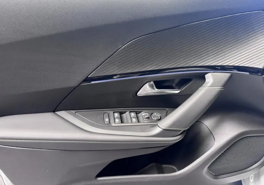 Détail de la porte avant gauche du Peugeot 2008 2026, avec commandes de vitres et insert décor carbone.