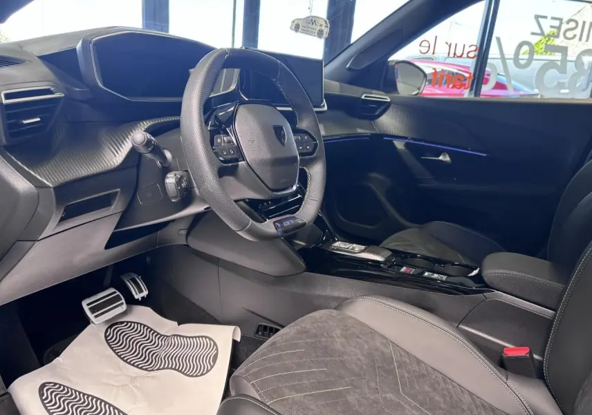 Vue intérieure côté conducteur du Peugeot 2008 1.2i Hybrid 2026, avec volant compact, sellerie Alcantara noire et surpiqûres vertes.