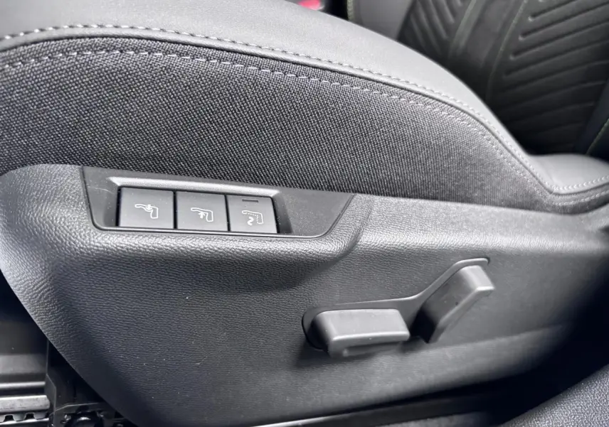 Détail des commandes de réglage électrique du siège conducteur en tissu noir du Peugeot 2008 Hybrid 2026.