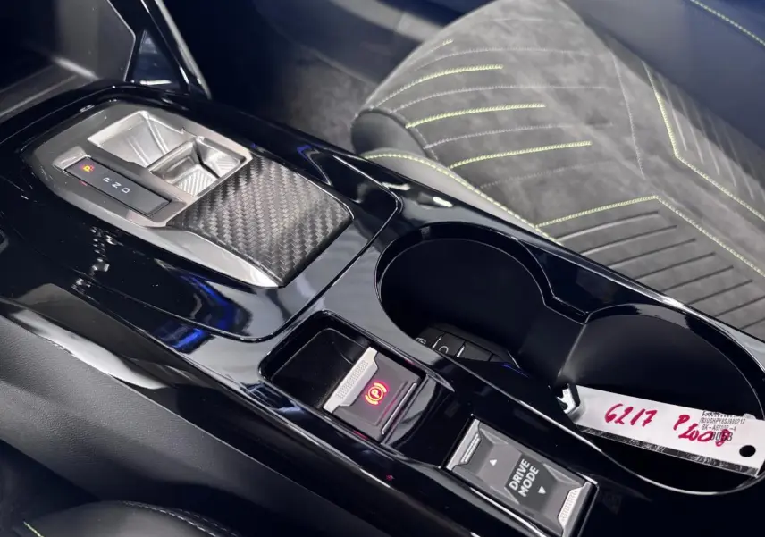 Vue rapprochée de la console centrale noire brillante avec levier de vitesses et sièges Alcantara noir surpiqués vert Adamite.