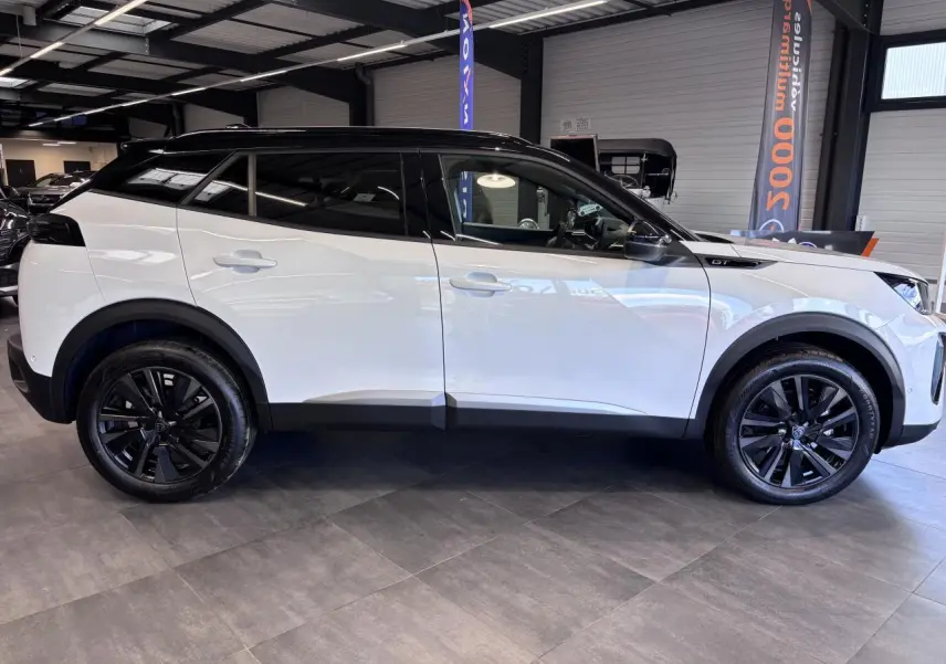 Peugeot 2008 1.2i Hybrid GT vue profil côté gauche, carrosserie blanche et toit noir avec jantes alliage noires.