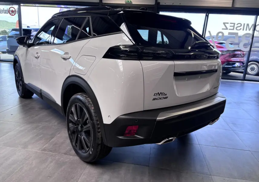 Vue 3/4 arrière droite du Peugeot 2008 hybride essence 2026 blanc avec toit noir et jantes alliage noires.