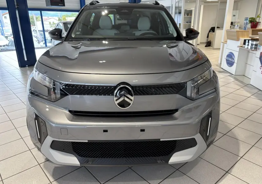 Vue avant d'un Citroën C3 Aircross 2026 gris métallisé avec toit noir et détails noirs brillants en showroom.