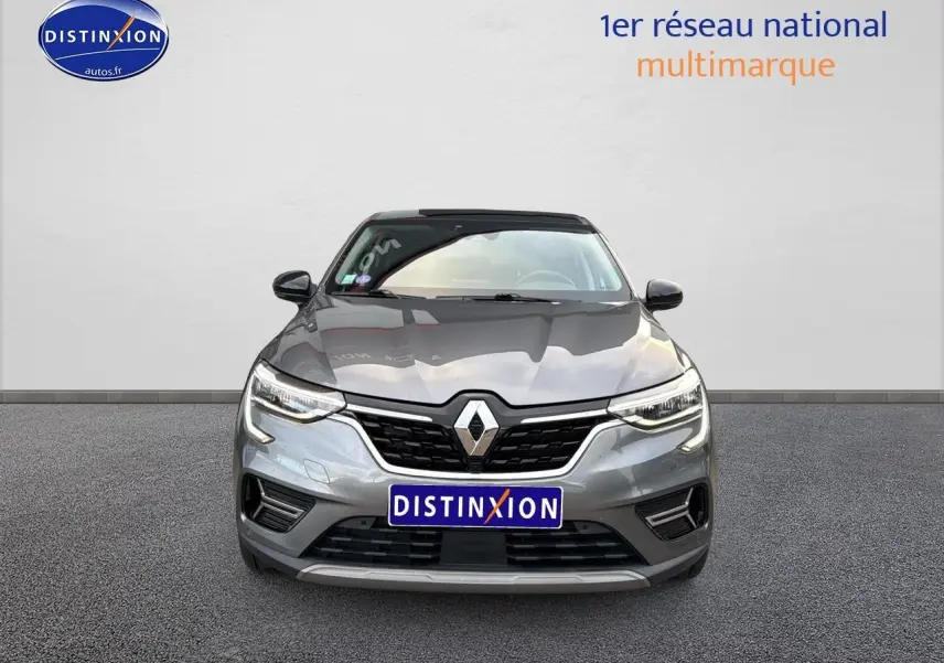 Vue avant d'un Renault Arkana gris 1.6 e-tech hybride 145 techno avec calandre noire et phares LED allumés.