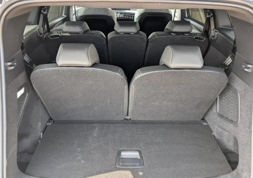 Vue arrière du coffre du Peugeot 5008 blanc 2025, montrant la banquette 3e rangée relevée et l'intérieur noir.