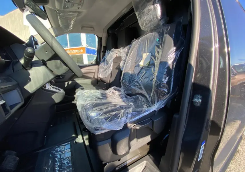 Vue intérieure côté conducteur du Peugeot Expert Fourgon gris titane, sièges protégés par film plastique.