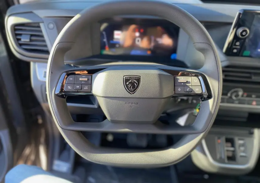 Vue rapprochée du volant Peugeot Expert Fourgon 2026 avec commandes intégrées et tableau de bord numérique flou.