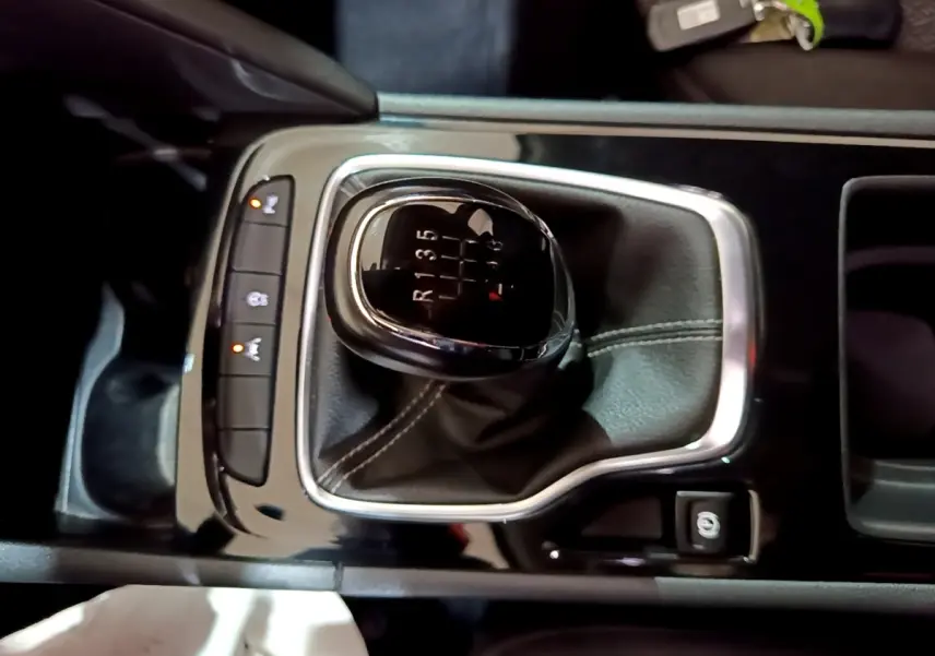 Gros plan sur levier de vitesses manuel noir et chrome dans console centrale d’Opel Insignia 2019, intérieur sombre.