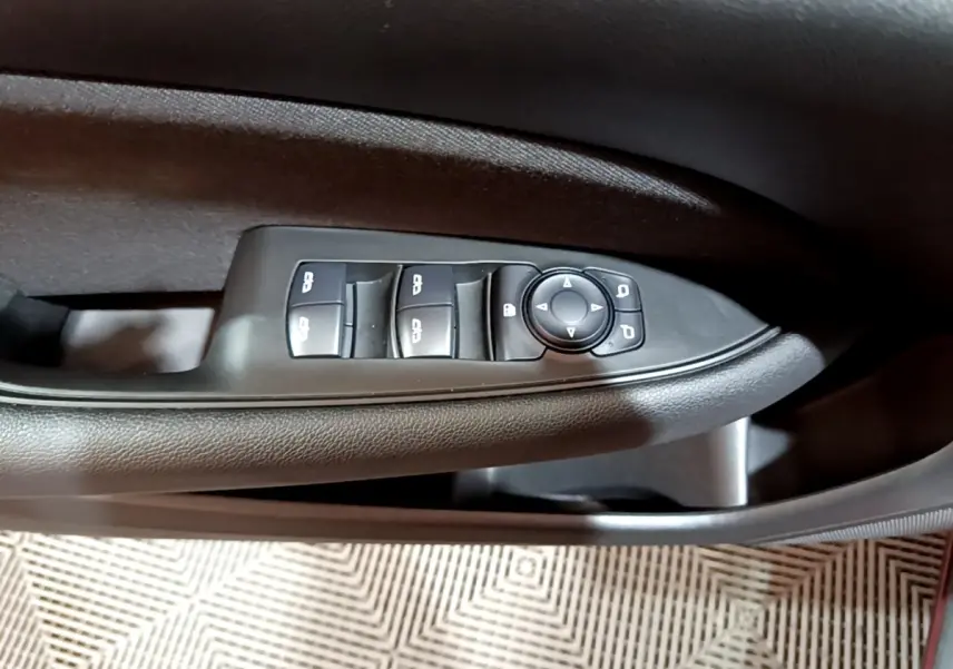 Détail des commandes de lève-vitres et rétroviseurs sur la porte côté gauche d’une Opel Insignia rouge 2019.