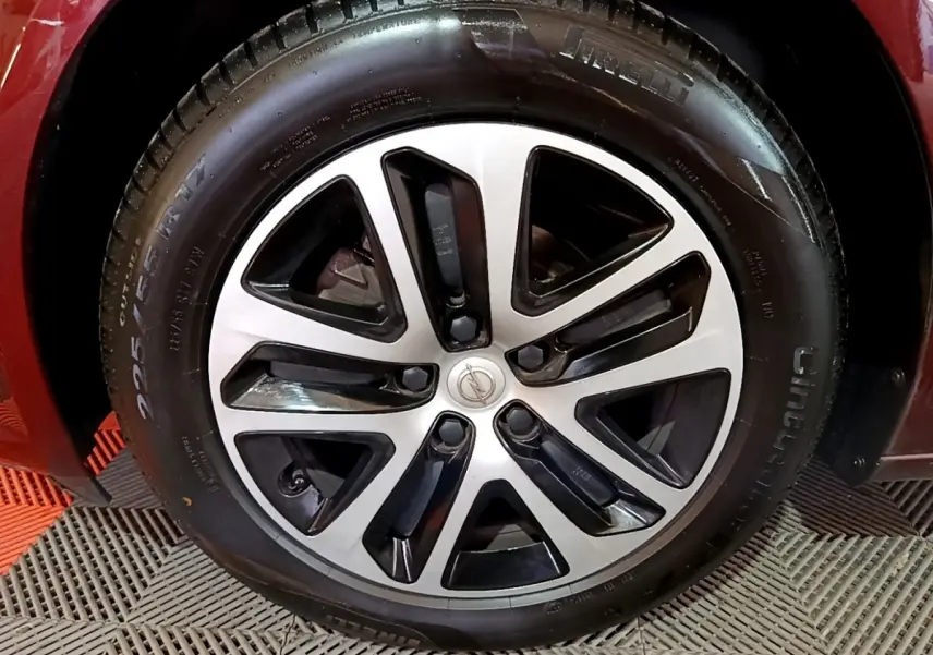 Gros plan sur la roue avant droite d’une Opel Insignia rouge, mettant en valeur le pneu et l’aile du véhicule.
