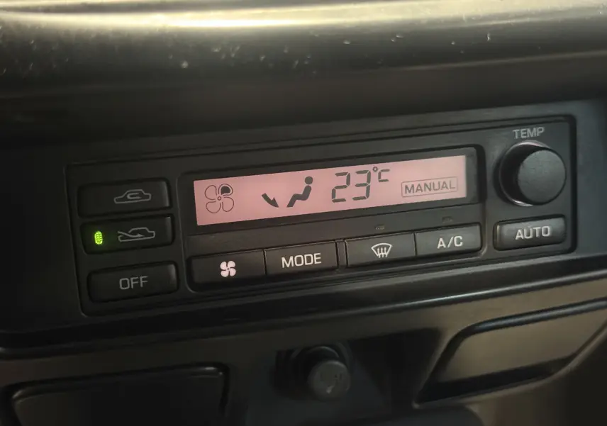 Détail de la console de climatisation numérique du Nissan Navara NP300 blanc, affichant 23°C en mode manuel.