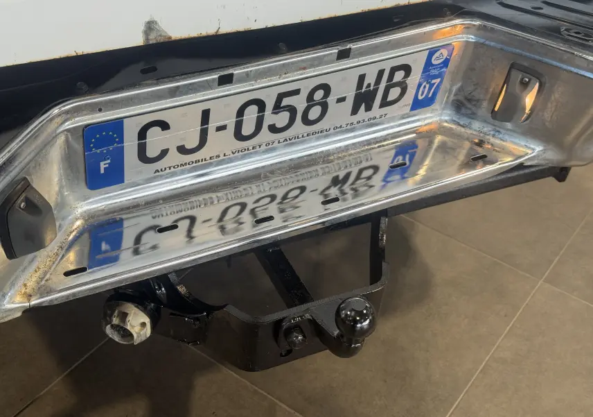 Gros plan sur la partie arrière blanche du Nissan Navara NP300 2002 avec attelage de remorque et plaque d'immatriculation française.