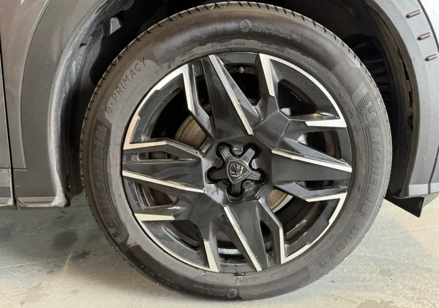 Gros plan sur la roue avant gauche gris foncé du Peugeot 5008 1.2 Hybrid 136 GT avec jante alliage noire et détails argentés.