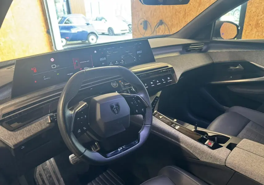 Vue intérieure du poste de conduite du Peugeot 5008 gris 1.2 Hybrid 136 GT, avec volant compact et grand écran numérique panoramique.