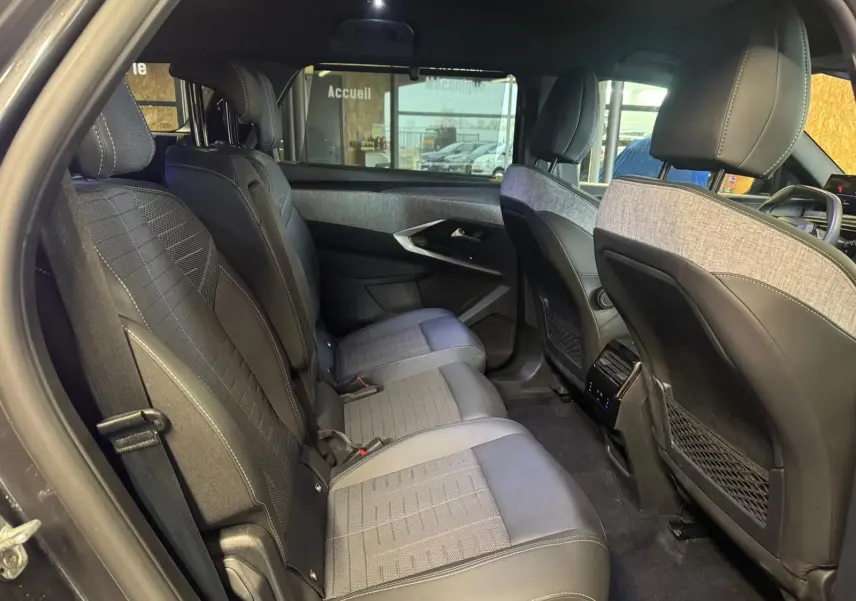 Vue intérieure arrière côté gauche du Peugeot 5008 gris 2025, montrant les sièges tissu noir et les finitions modernes des portes.