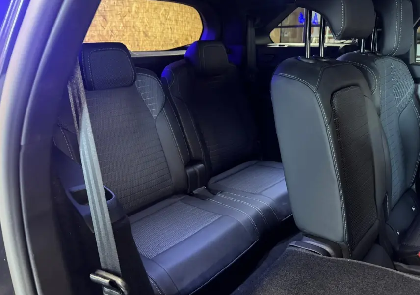 Vue intérieure arrière du Peugeot 5008 gris 2025, montrant les sièges en tissu noir avec surpiqûres blanches.