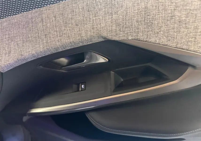 Détail de la porte intérieure côté gauche du Peugeot 5008 gris, avec poignée argentée et commande de vitre.