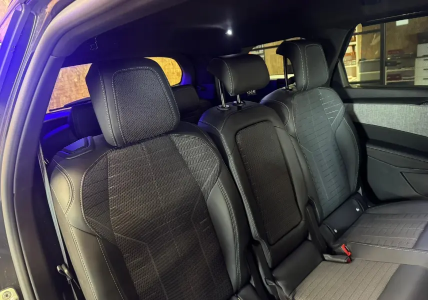 Vue intérieure des sièges arrière en tissu noir avec surpiqûres blanches du Peugeot 5008 1.2 Hybrid 136 GT gris 2025.