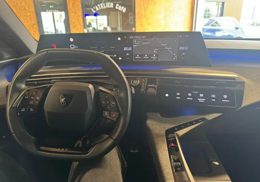 Vue intérieure du poste de conduite du Peugeot 5008 gris 2025, avec volant compact et tableau de bord numérique panoramique.