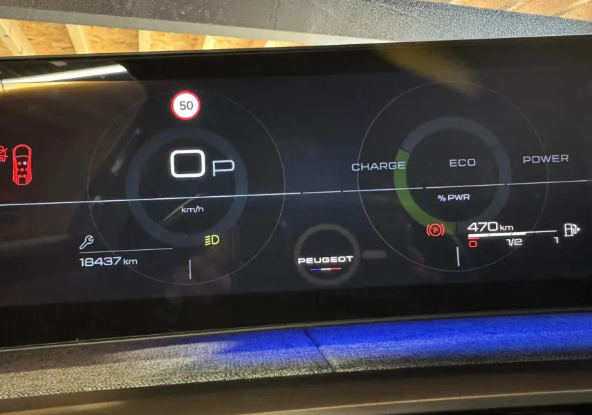 Tableau de bord numérique du Peugeot 5008 gris 2025, affichant vitesse, autonomie et indicateurs hybrides.