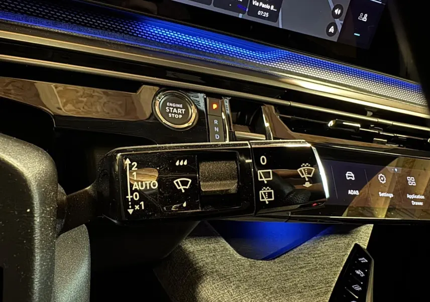 Gros plan sur la commande d’essuie-glace du tableau de bord du Peugeot 5008 gris hybride 2025, avec éclairage bleu ambiant.