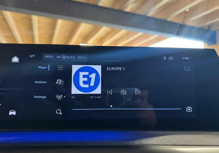 Écran tactile intérieur du Peugeot 5008 gris 2025 affichant la radio Europe 1 avec ambiance lumineuse bleue.
