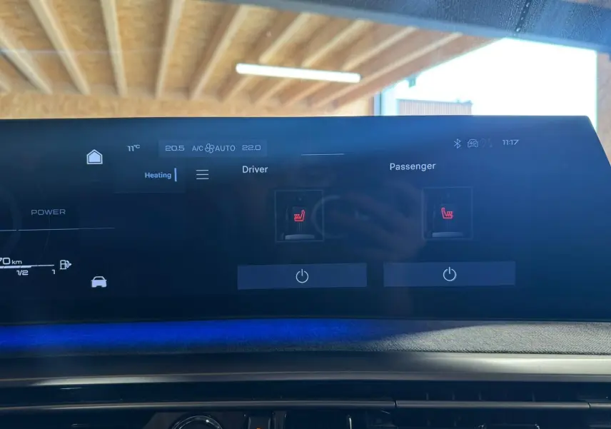Écran tactile intérieur du tableau de bord du Peugeot 5008 gris 1.2 Hybrid 136 GT, affichant les commandes de chauffage des sièges.