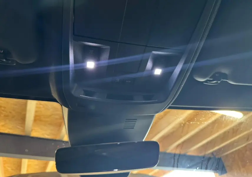 Vue intérieure en plongée sur le plafonnier et le rétroviseur d’un Peugeot 5008 gris hybride 2025.