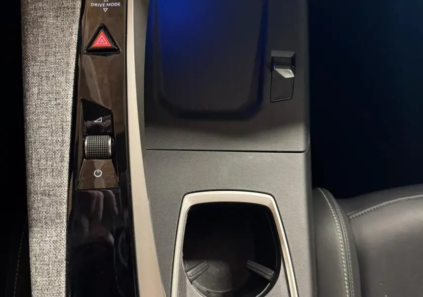 Vue plongeante sur la console centrale noire et grise du Peugeot 5008 1.2 Hybrid 136 GT avec porte-gobelets et commandes tactiles.