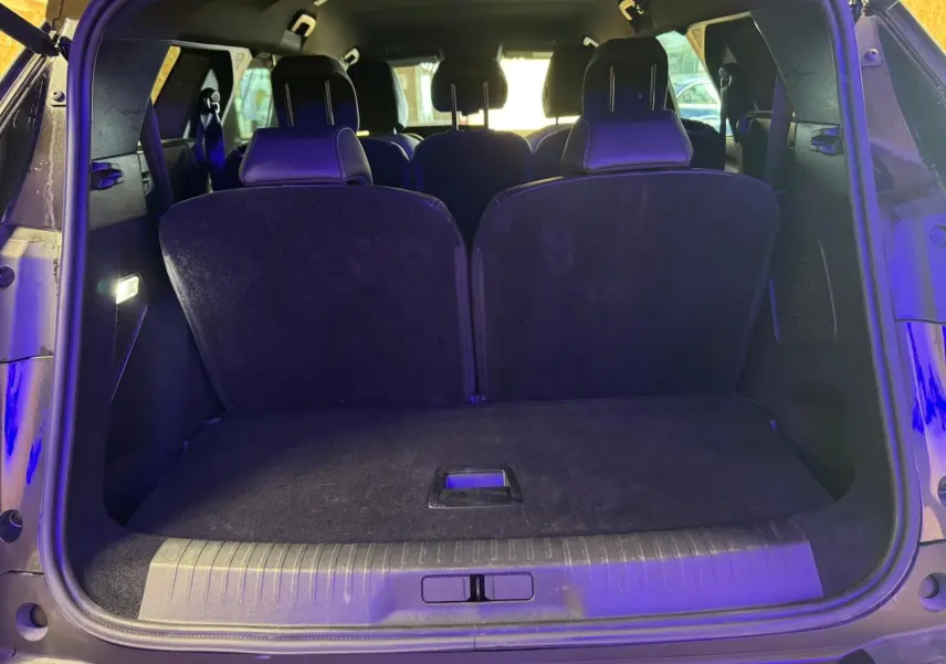 Coffre ouvert vu de l'arrière d'un Peugeot 5008 gris, montrant les sièges arrière et l'espace de chargement.