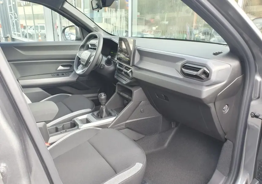 Intérieur avant droit du Dacia Dokker Van gris schiste, avec tableau de bord moderne et boîte manuelle visible.