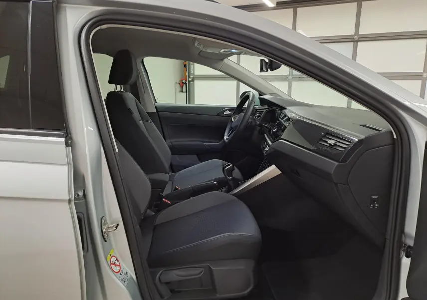Vue intérieure côté conducteur du Volkswagen Taigo 2025 argent, montrant sièges noirs et tableau de bord moderne.