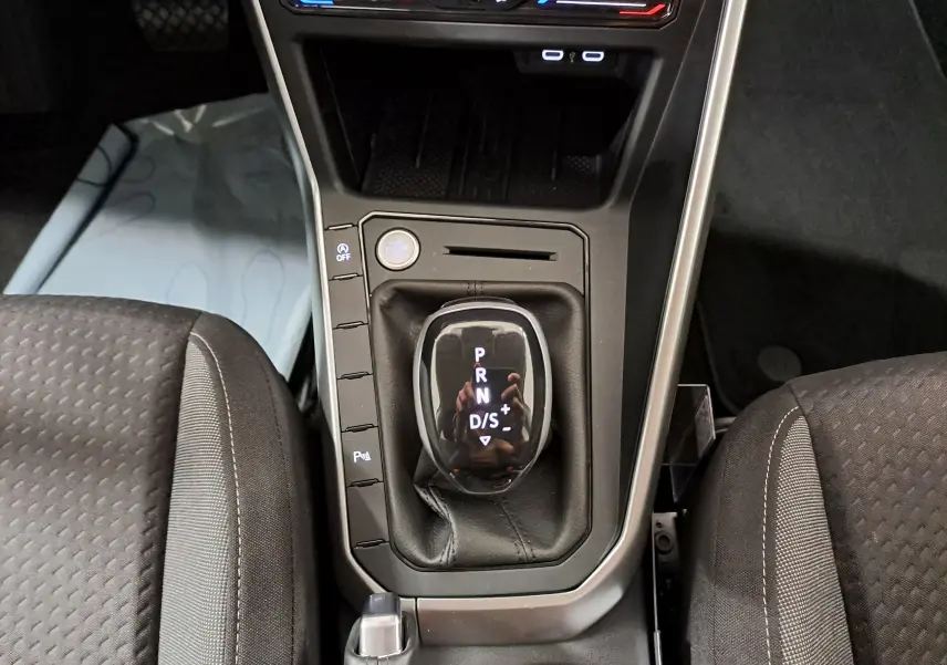 Vue plongeante sur la console centrale du Volkswagen Taigo 2025, avec levier de vitesse automatique et sièges tissu gris.