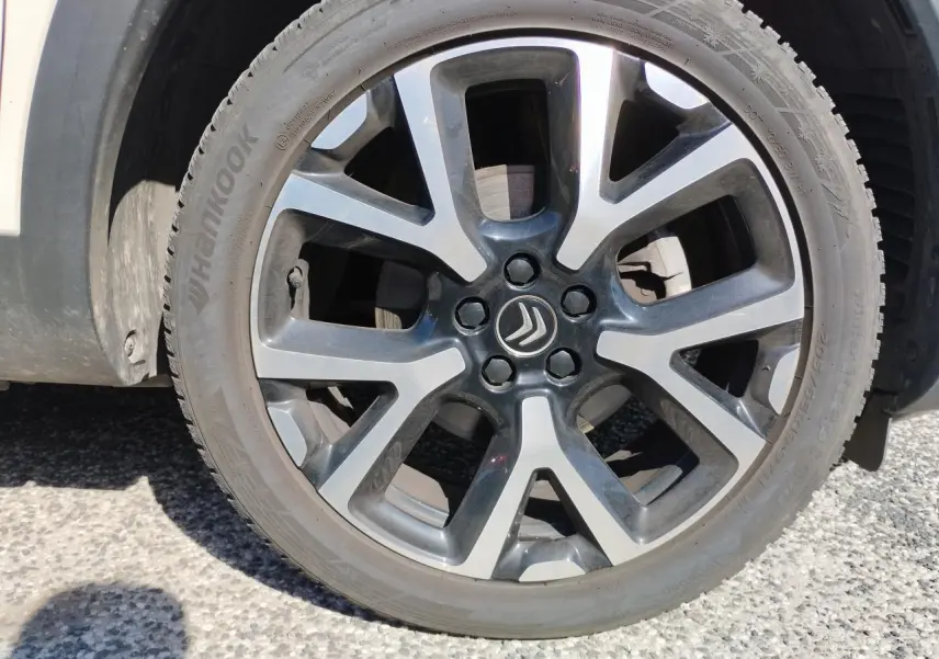 Gros plan sur la jante alliage bi-ton noir et argentée d’un Citroën C5 Aircross blanc nacré.
