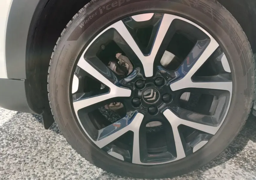 Gros plan sur la jante alliage bi-ton noire et argentée du côté avant droit du Citroën C5 Aircross blanc nacré.